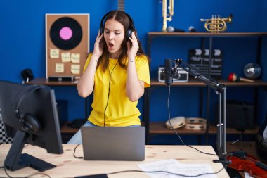 Kulaklık takıp müzik dinleyen, ağzı açık, korkmuş, şaşırmış genç İspanyol kız. 