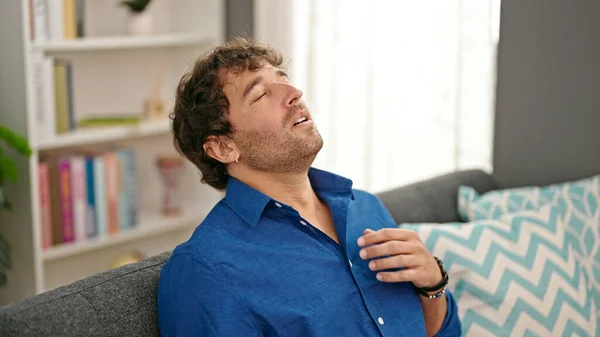 Young hispanic man relaxed on sofa at home