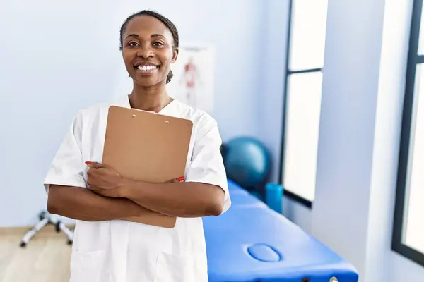 African American Woman Physiotherapist Smiling Confident Holding Medical Report Rehab — Stok fotoğraf