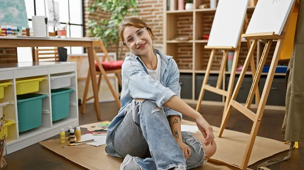 年轻的女艺术家充满自信地坐在艺术工作室的地板上 — 图库照片