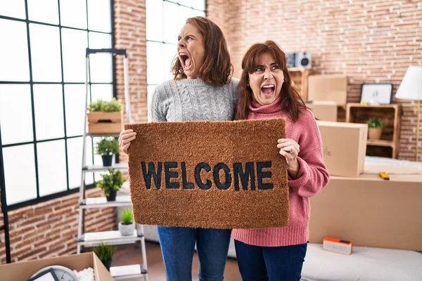 Mother Daughter Holding Welcome Doormat Angry Mad Screaming Frustrated Furious — Stock Photo, Image