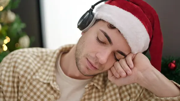 Mladý Hispánec Muž Spí Pohovce Vánočního Stromku Nosí Sluchátka Doma — Stock fotografie