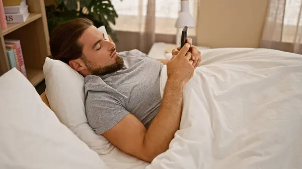 Jonge Spaanse Man Met Behulp Van Smartphone Liggend Bed Slaapkamer — Stockfoto