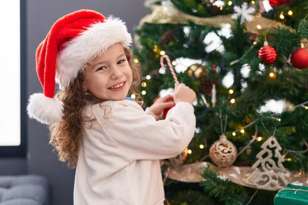 自宅でクリスマスツリーを飾る自信を持って微笑む愛らしいブロンドの幼児 — ストック写真