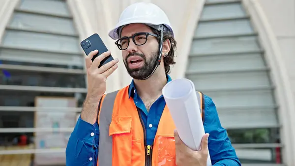 Young Hispanic Man Architect Holding Blueprints Sending Voice Message Smartphone — Stock Photo, Image