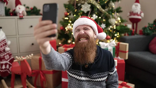 남자는 집에서 크리스마스 트리에 바닥에 스마트 폰으로 셀카를 만듭니다 — 스톡 사진
