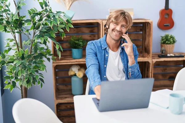 Genç Adam Dizüstü Bilgisayar Kullanıyor Evde Akıllı Telefonla Konuşuyor — Stok fotoğraf