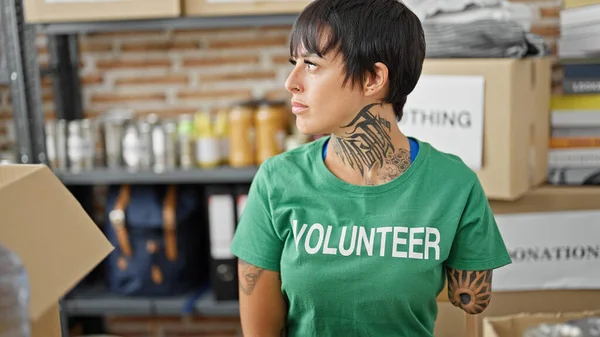 Hispanic woman with amputee arm volunteer sitting on table with serious face at charity center