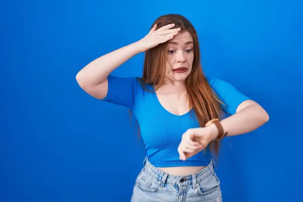 Kızıl Saçlı Kadın Mavi Arka Planda Dikiliyor Saate Bakıyor Endişeli — Stok fotoğraf