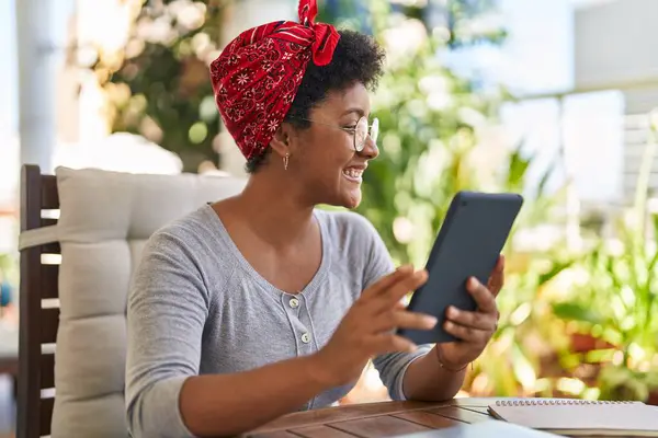 African american woman using touchpad sitting on table at home terrace