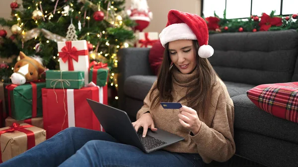 Beautiful hispanic woman shopping with laptop and credit card celebrating christmas at home