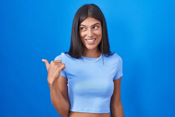 Esmer Genç Bir Kadın Mavi Arka Planda Gülümsüyor Gülümsüyor Başparmağıyla — Stok fotoğraf