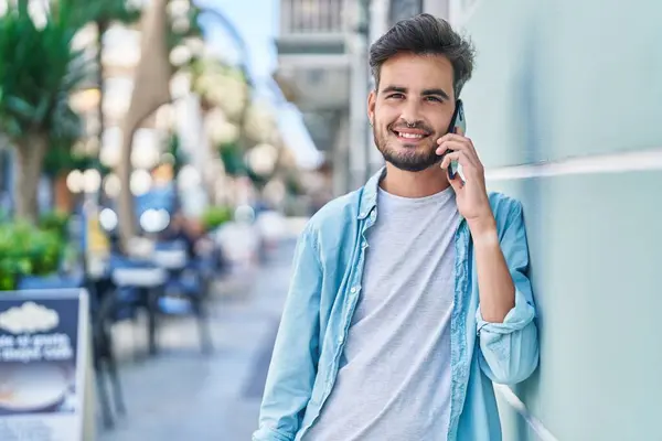 Genç İspanyol adam gülümsüyor. Kendine güveniyor. Sokakta akıllı telefondan konuşuyor.