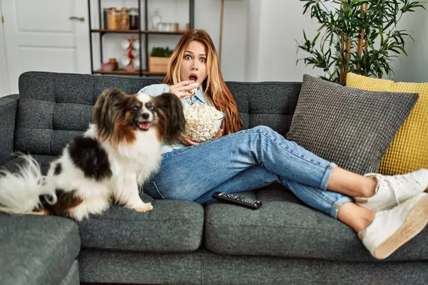 Young Caucasian Woman Surprised Watching Movie Sitting Sofa Dog Home — ストック写真