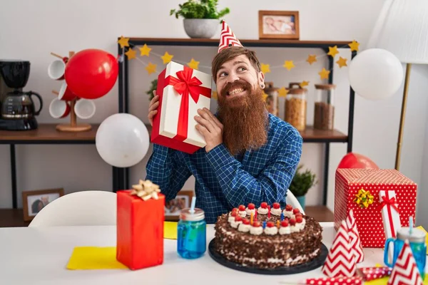Young Redhead Man Celebrating Birthday Holding Gift Home — Stok fotoğraf