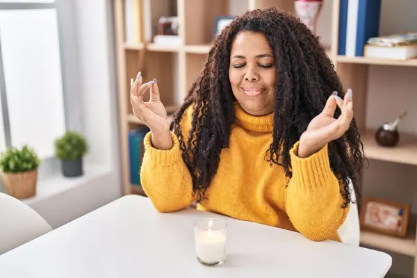 African american woman doing yoga exercise sitting on table at home