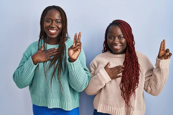 Two African Woman Standing Blue Background Smiling Swearing Hand Chest — Stock Photo, Image