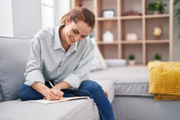 Young Woman Writing Notebook Sitting Sofa Home —  Fotos de Stock
