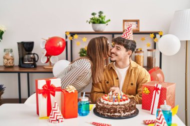 Mand and woman couple having birthday celebration kissing at home