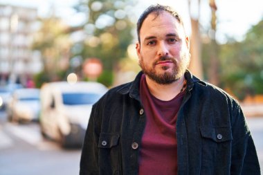 Young hispanic man with relaxed expression standing at street