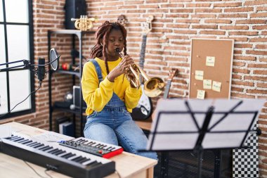 Afrikalı Amerikalı kadın müzisyen müzik stüdyosunda trompet çalıyor.