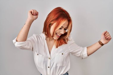 Young caucasian woman standing over isolated background dancing happy and cheerful, smiling moving casual and confident listening to music 