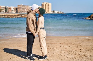 Mand and woman couple standing together kissing at seaside