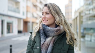 Young blonde woman smiling confident looking to the side at street