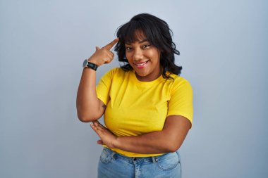 Mavi arka planda durup gülümseyen İspanyol kadın tek parmağıyla kafasını işaret ediyor, harika bir fikir ya da düşünce, iyi bir hafıza. 