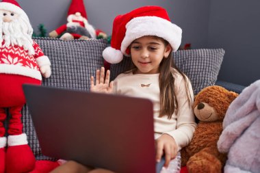 Noel şapkası takan sevimli İspanyol kız evde video görüşmesi yapıyor.