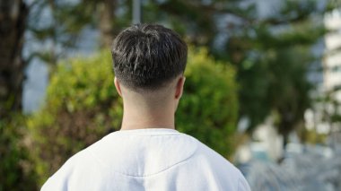 Parkta arkada duran İspanyol genç adam.