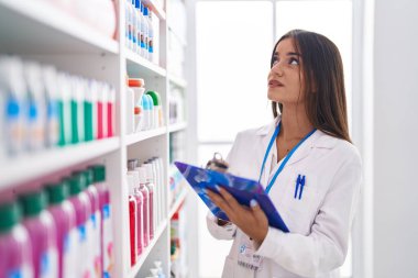 Genç, güzel İspanyol kadın eczacı eczanedeki belgeye yazı yazıyor.