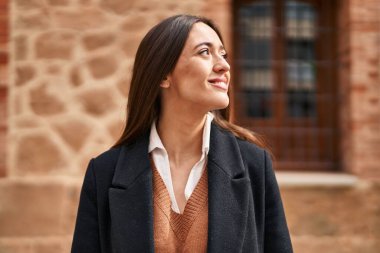 Young beautiful hispanic woman smiling confident looking to the side at street