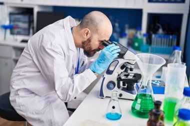 Genç kel bilim adamı laboratuvarda mikroskop kullanıyor.