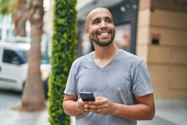 Sokakta akıllı telefon kullanan, kendine güvenen genç Latin adam.