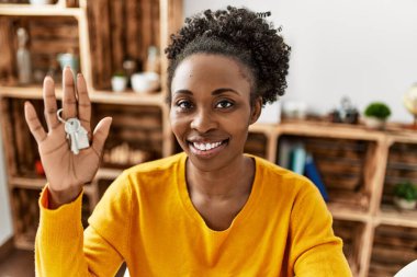 African american woman smiling confident holding key of new house at home