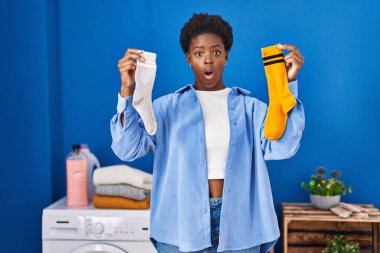 Afro-Amerikalı kadın temiz Andy kirli çoraplarını tutuyor. Şaşırmış ve şaşırmış bir ifade, korku ve heyecanlı bir yüz ifadesi var.. 