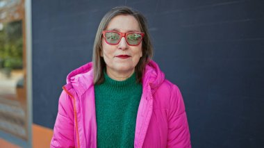 Sokak ortasında güneş gözlüğü takan, gri saçlı, olgun İspanyol bir kadın.