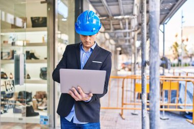 Young man architect using laptop at street