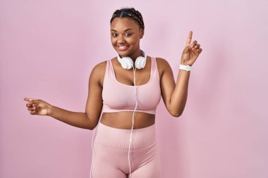 Saçları örgülü, kulaklık takan ve gülümseyen, kendine güvenen, farklı yönleri gösteren Afro-Amerikalı bir kadın. reklam için kopyalama alanı 