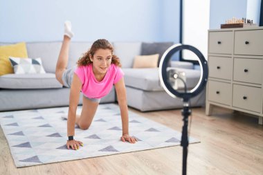 Young beautiful hispanic woman smiling confident having online legs training class at home