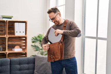 Young caucasian man business worker holding laptop of briefcase at office