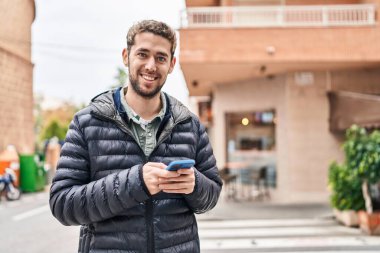 Sokakta akıllı telefon kullanan kendine güvenen genç adam.