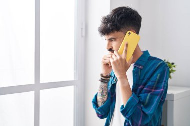 Genç İspanyol adam evde akıllı telefondan konuşmaktan endişeleniyor.