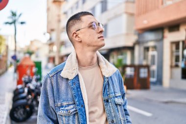 Young hispanic man looking to the sky with relaxed expression at street