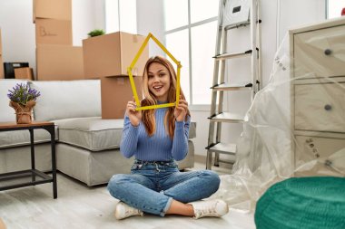 Kafkasyalı genç bir kadın ev projesini tutuyor. Yeni evinde yerde oturuyor.