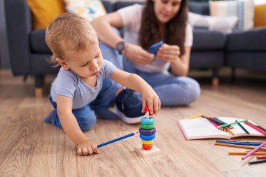 Anne ve oğlu akıllı telefon kullanarak yerde oturuyor ve evde oynuyorlar.