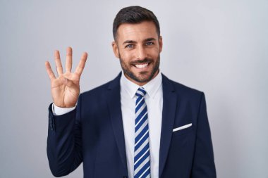 Yakışıklı İspanyol takım elbiseli ve kravatlı adam dört numarayı gösterip işaret ederken kendinden emin ve mutlu gülümsüyor.. 