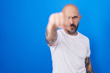 Dövmeleri olan İspanyol bir adam mavi arka planda duruyor. Yumruklarını yumrukluyor, saldırıyor, saldırıyor, tehdit ediyor ve şiddet uyguluyor. 