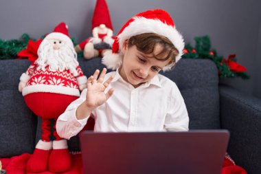 Sevimli İspanyol çocuk evdeki Noel süslemeleriyle birlikte koltukta oturuyor.